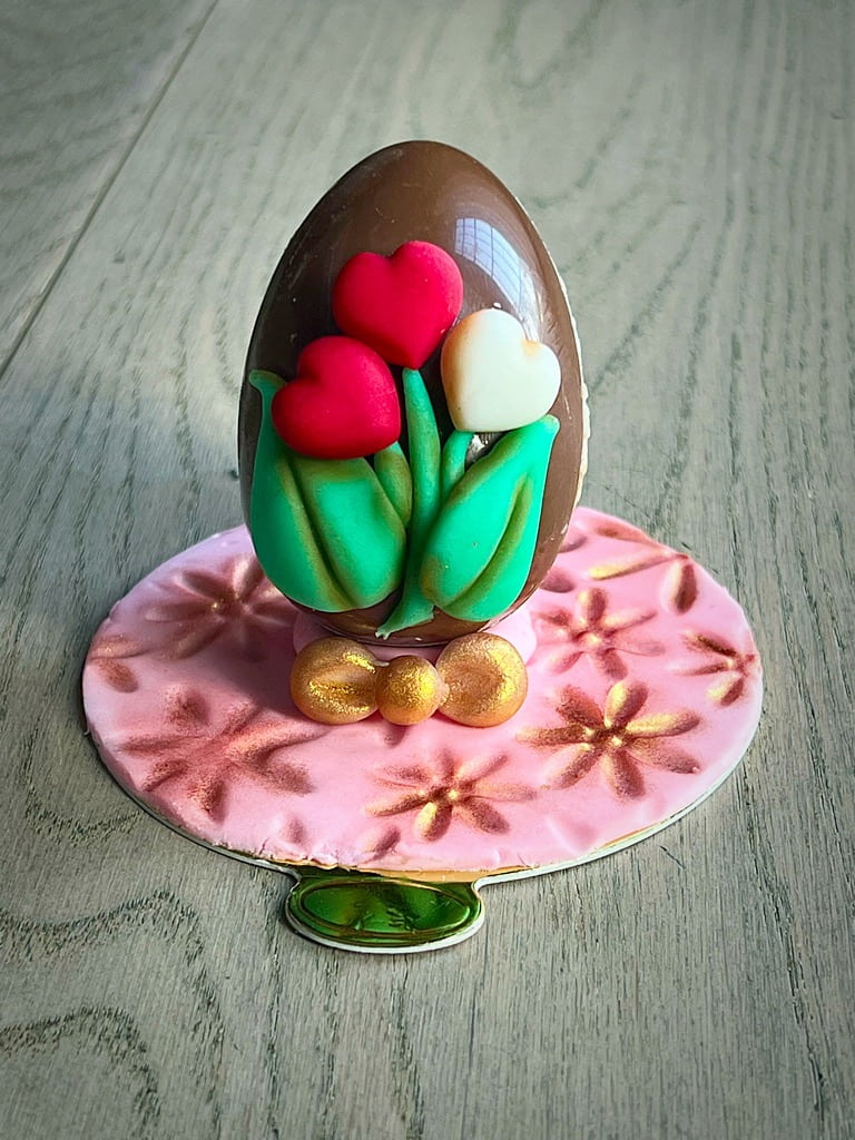 uovo di cioccolato decorato con un mazzo di cuori bianchi e rossi